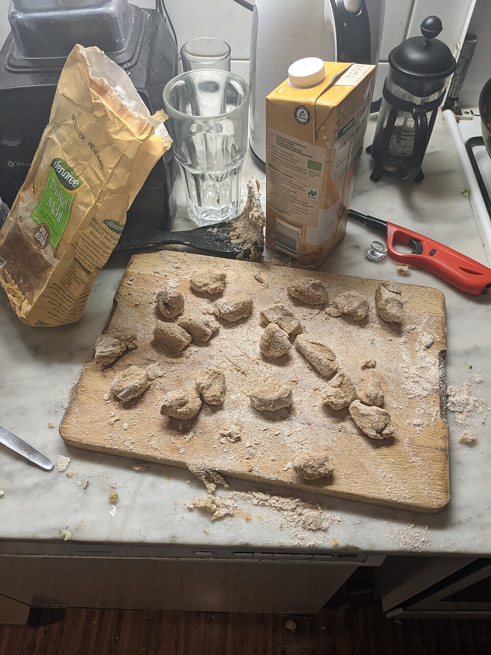 A kitchen plate with freshly formed gnocchi on a wooden board. Flour is everywhere.